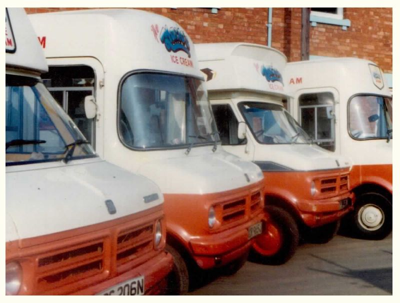 Vintage Ice Cream vans lined up outside of factory.